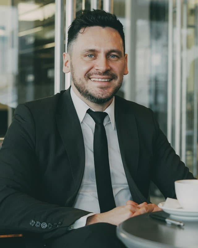 A smiling man in a suit at a café table